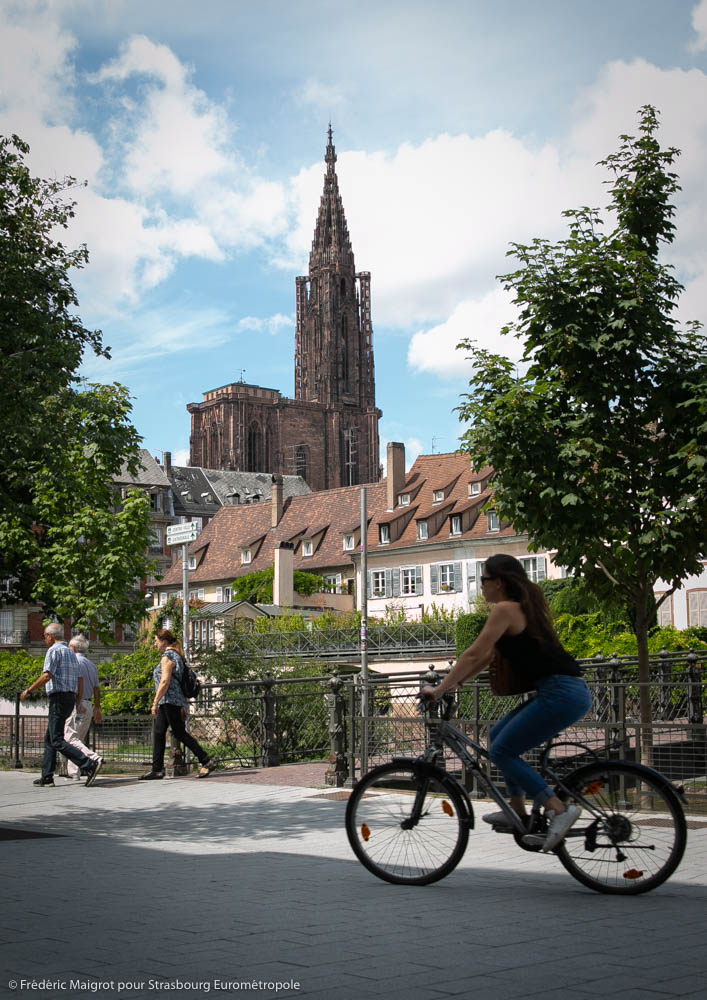 une femme roule à vélo sur les Quais des Bateliers de Strasbourg en vélo