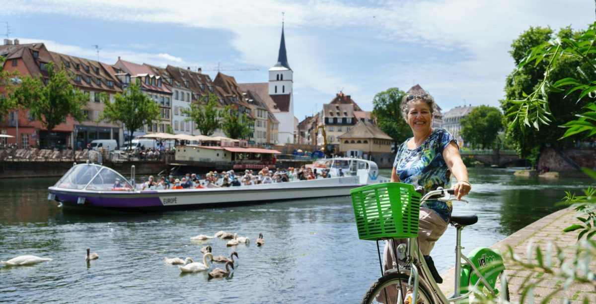 Femme souriante sur un vélo et bateau de croisière qui passe